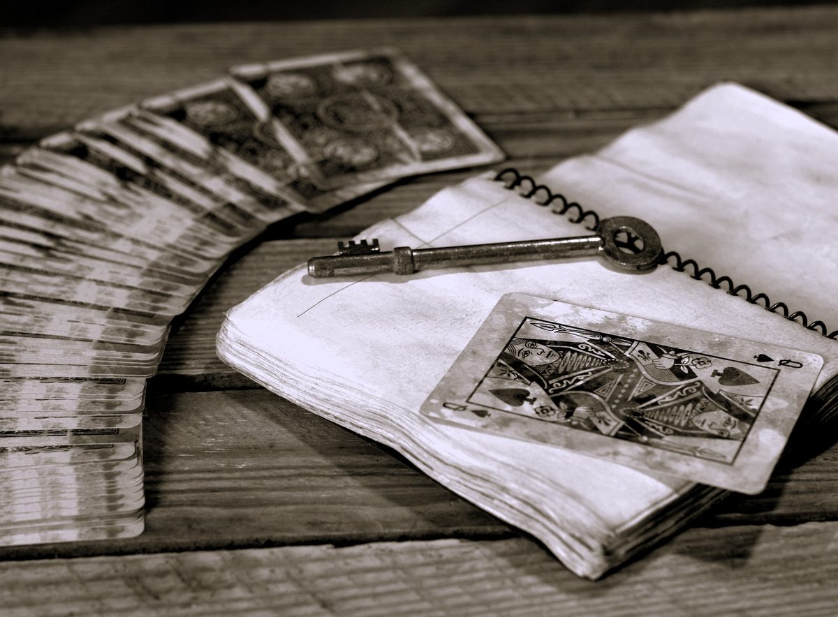 Jeu de cartes anciennes, vieux carnet et clé en métal posés sur une table en bois